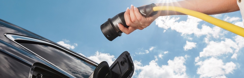 Imagen de una mujer cargando su coche eléctrico