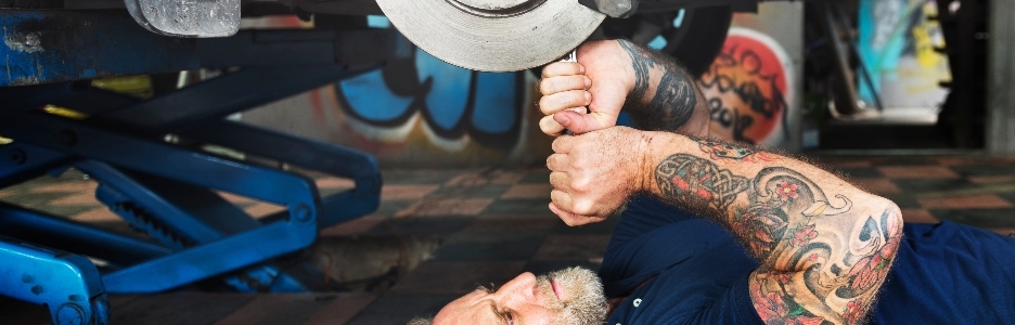 Imagen de un mecánico masculino arreglando un coche en el taller