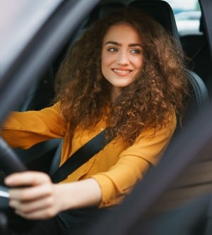 Imagen de una mujer joven conduciendo un automóvil en la ciudad retrato de una hermosa mujer en un automóvil mirando por la ventana y sonriendo