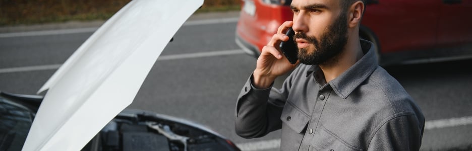 Imagen de un hombre hace llamadas de teléfono celular frente al capó abierto de un automóvil averiado en la carretera. Concepto de avería del automóvil forestal.