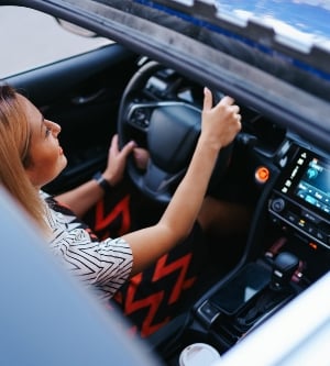Imagen de una mujer joven conduciendo con techo corredizo abierto