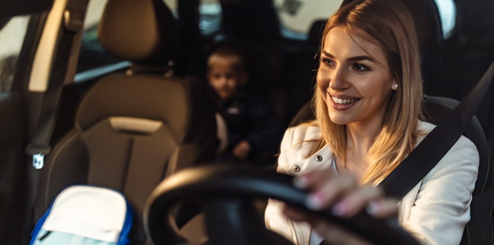 Imagen de una mujer conduciendo su coche con su hijo en el asiento de atrás