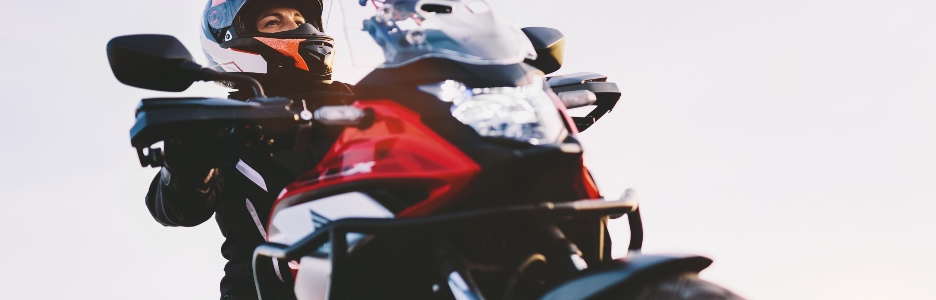 Imagen de una mujer en moto mirando el atardecer