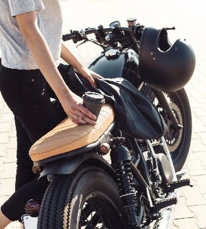 Imagen de una muchacha atractiva joven con la taza de café y de la motocicleta de encargo de la vendimia. Al aire libre retrato estilo de vida.