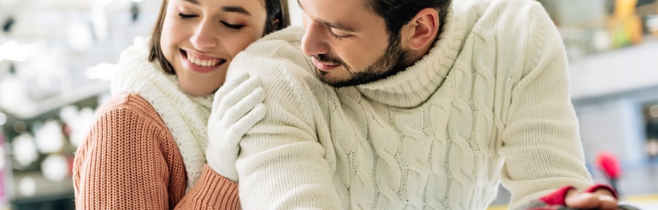 Imagen de hermosa pareja alegre en suéteres pasando tiempo en la pista de patinaje