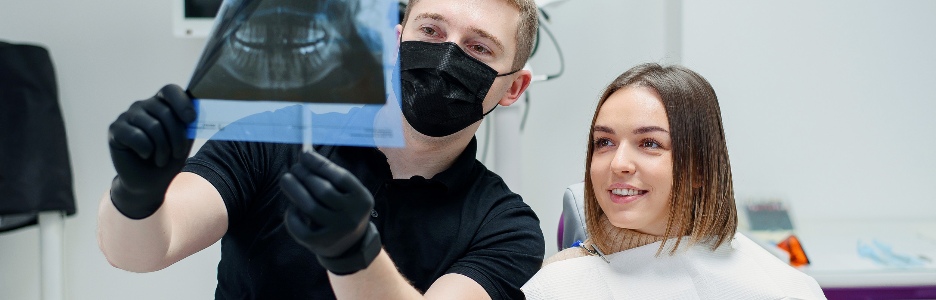 Imagen de un dentista altamente calificado le muestra a la joven paciente una radiografía de los dientes en el sillón dental de la clínica moderna