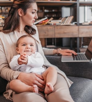 Imagen de madre sentada en el sofá con su hijo y usando la computadora portátil en casa