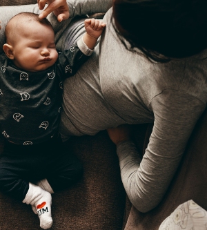 Imagen de una madre de reposo en el sofá con su bebé encima de ella