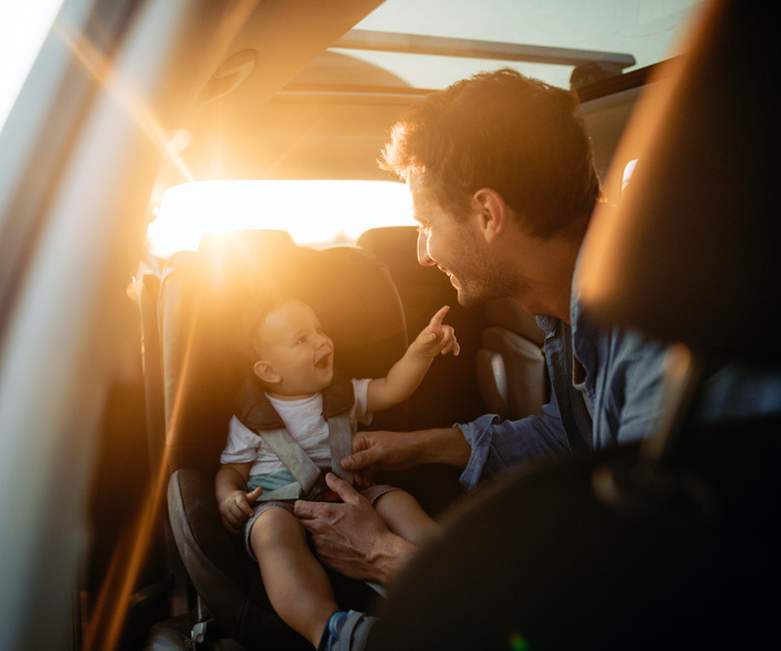 Imagen de un padre poniendo su hijo en el asiento bebé de su coche
