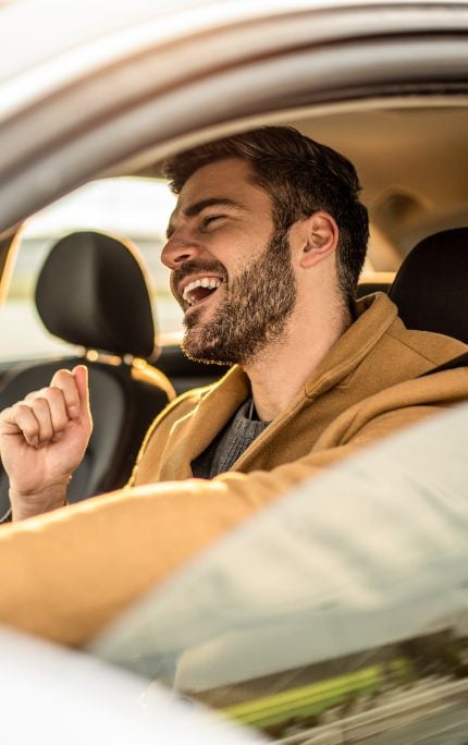 chico muy contento conduciendo un coche