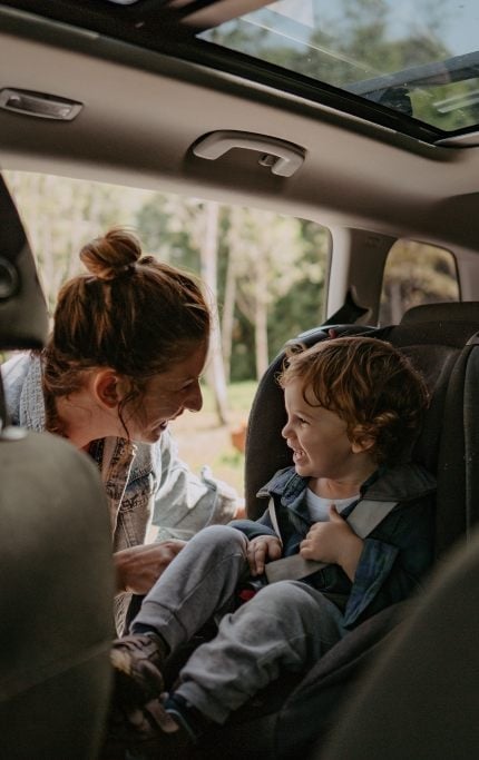 madre sentando un niñi pequeño en la sillita del coche