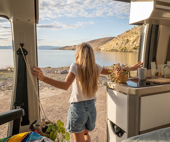Imagen de una mujer saliendo de su furgoneta camper